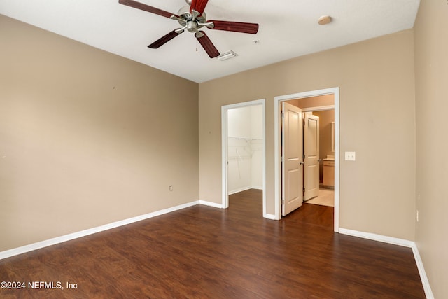 unfurnished bedroom featuring dark hardwood / wood-style flooring, a spacious closet, a closet, and ceiling fan