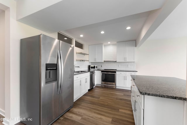 kitchen featuring backsplash, white cabinetry, dark stone countertops, dark hardwood / wood-style floors, and stainless steel appliances