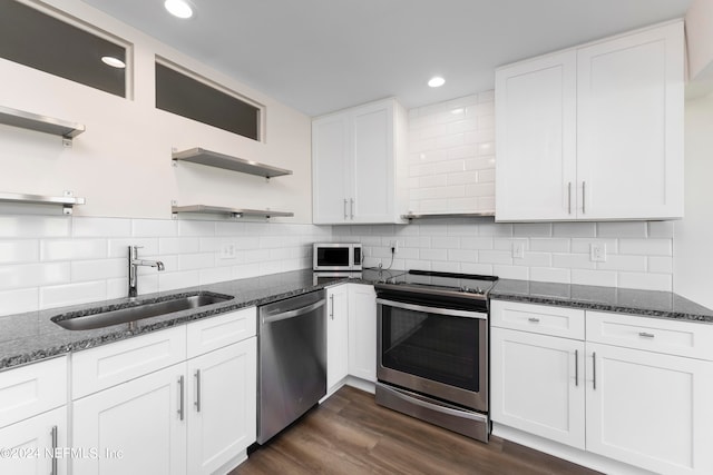 kitchen with stainless steel appliances, sink, dark hardwood / wood-style flooring, white cabinets, and tasteful backsplash