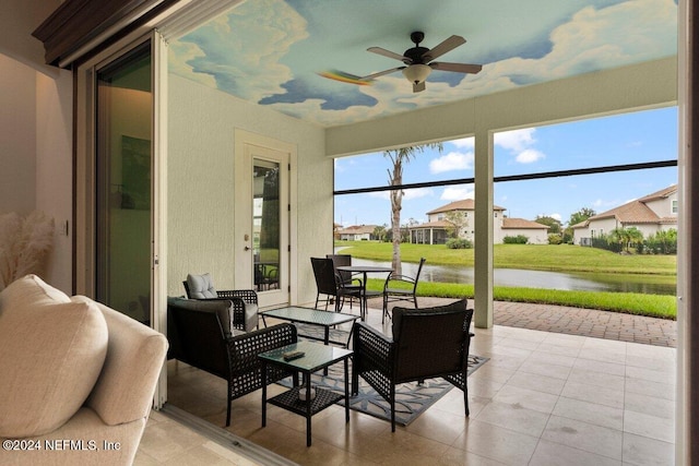 sunroom featuring a water view and ceiling fan