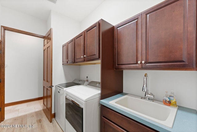 washroom featuring cabinets, independent washer and dryer, sink, and light hardwood / wood-style floors