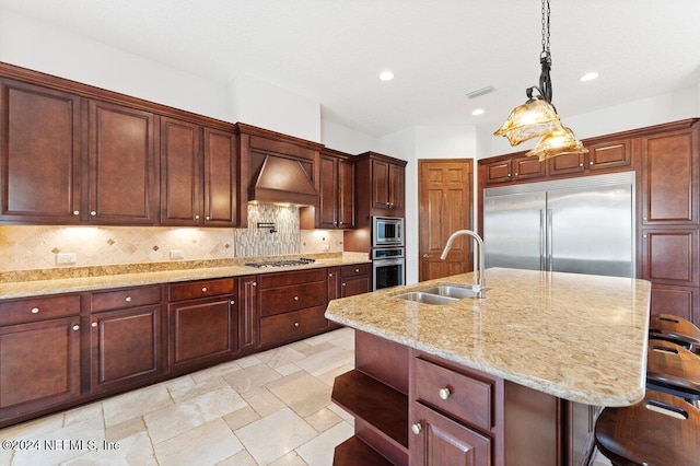 kitchen featuring built in appliances, custom range hood, decorative backsplash, and an island with sink