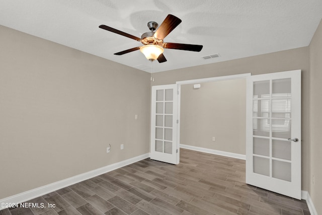 unfurnished room with french doors, ceiling fan, a textured ceiling, and hardwood / wood-style floors