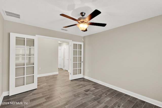 spare room featuring french doors, dark hardwood / wood-style floors, a textured ceiling, and ceiling fan