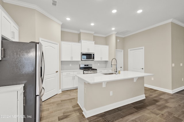 kitchen with white cabinets, hardwood / wood-style floors, appliances with stainless steel finishes, a kitchen island with sink, and sink