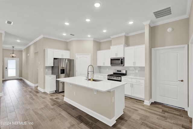 kitchen with white cabinets, a center island with sink, light hardwood / wood-style flooring, sink, and stainless steel appliances