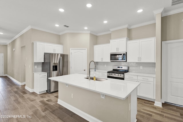 kitchen with appliances with stainless steel finishes, white cabinetry, a kitchen island with sink, and sink