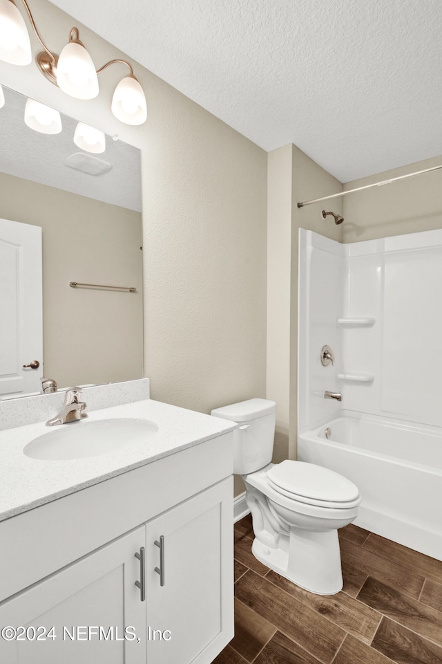 full bathroom featuring vanity, toilet, a textured ceiling, and washtub / shower combination