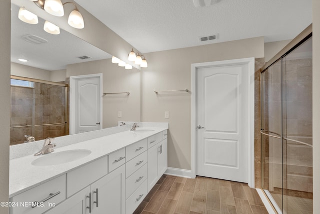 bathroom featuring vanity, a textured ceiling, and a shower with door