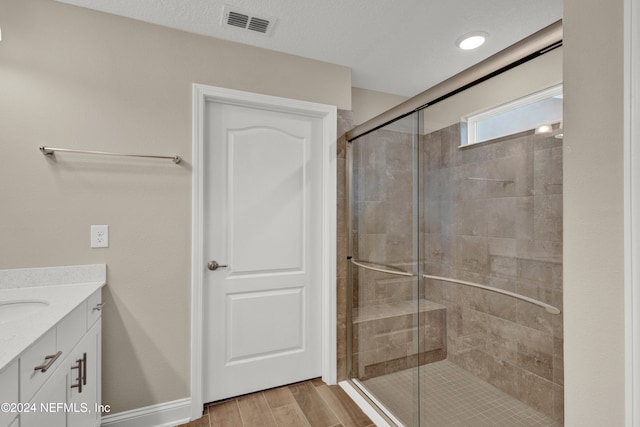 bathroom featuring vanity, a textured ceiling, a shower with shower door, and hardwood / wood-style flooring