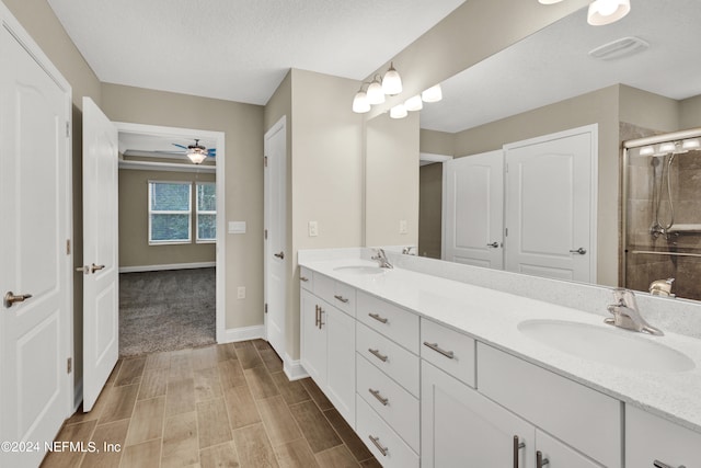 bathroom featuring vanity, ceiling fan, a textured ceiling, and an enclosed shower