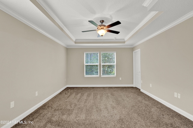 carpeted spare room with crown molding, a tray ceiling, and ceiling fan