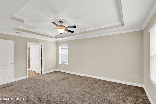 unfurnished bedroom with ceiling fan, ornamental molding, a tray ceiling, and light colored carpet