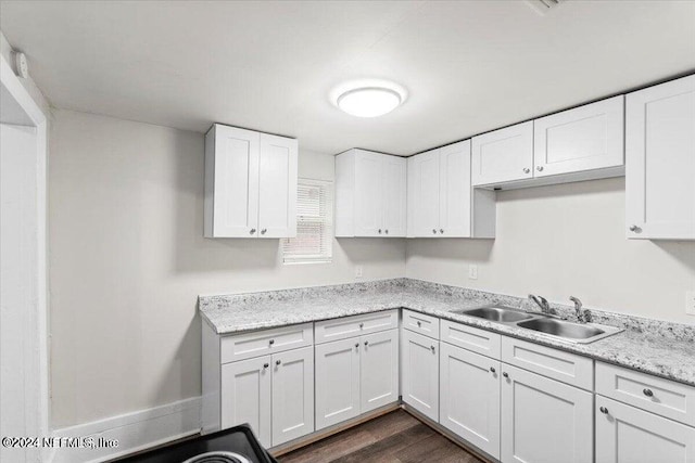 kitchen with dark wood-type flooring, light stone countertops, sink, and white cabinets