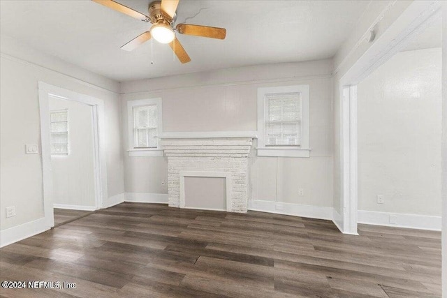 unfurnished living room featuring dark wood-type flooring, ceiling fan, and a fireplace