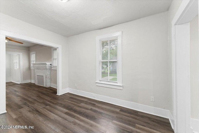 unfurnished living room with a textured ceiling, ceiling fan, and dark hardwood / wood-style flooring