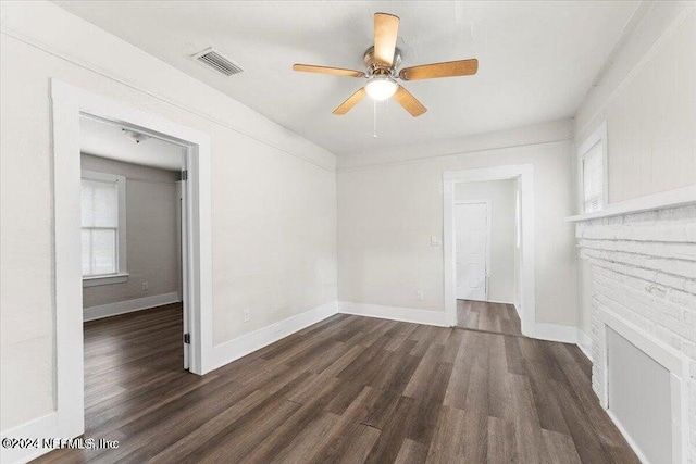 unfurnished living room featuring ceiling fan, a brick fireplace, and dark hardwood / wood-style floors