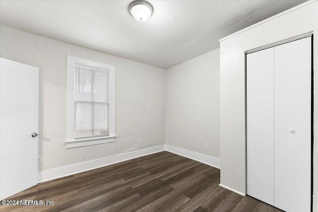 unfurnished bedroom featuring a closet and dark hardwood / wood-style flooring