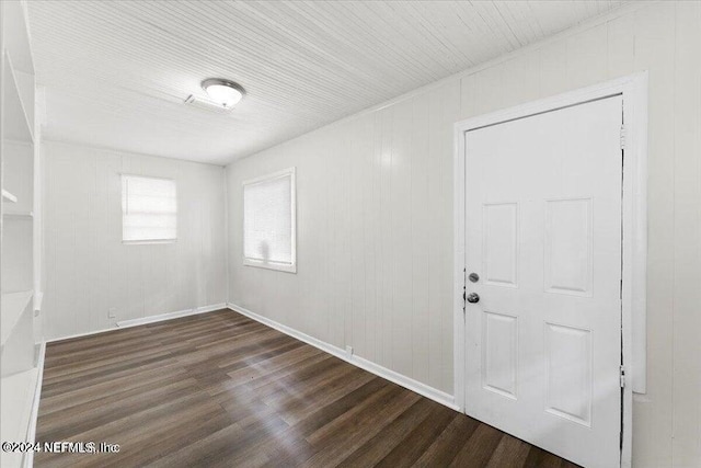 unfurnished room with wood walls and dark wood-type flooring