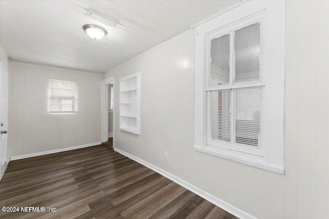 unfurnished room featuring wooden walls and dark hardwood / wood-style flooring