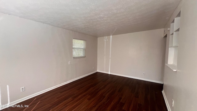 unfurnished room featuring a textured ceiling and dark hardwood / wood-style floors