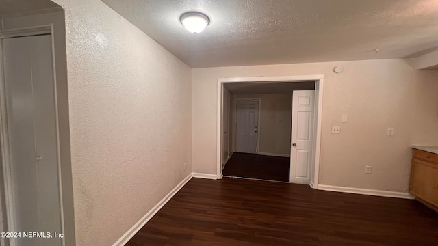 hall featuring lofted ceiling, a textured ceiling, and dark hardwood / wood-style flooring