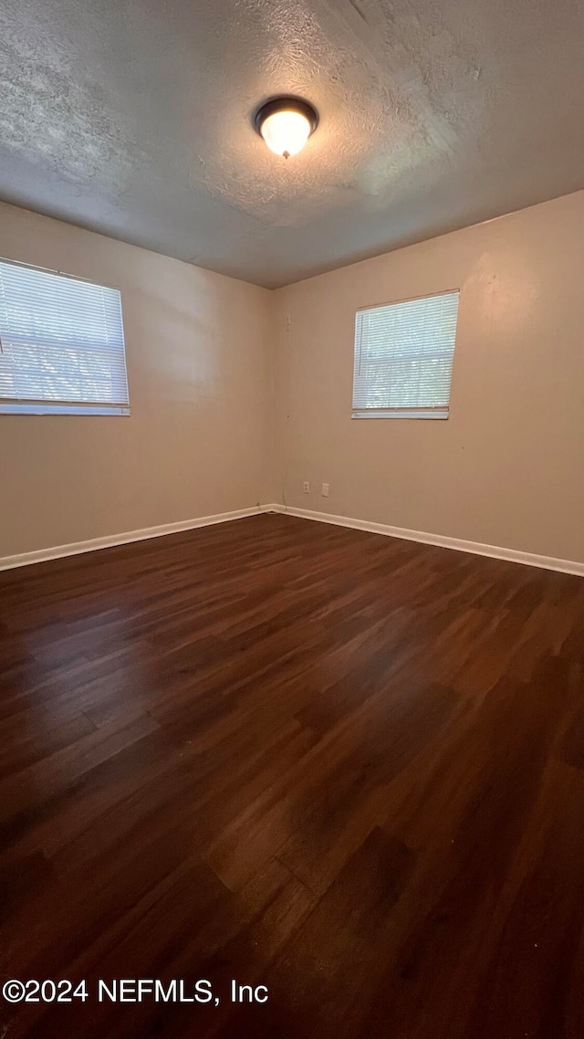 spare room with dark wood-type flooring and a textured ceiling