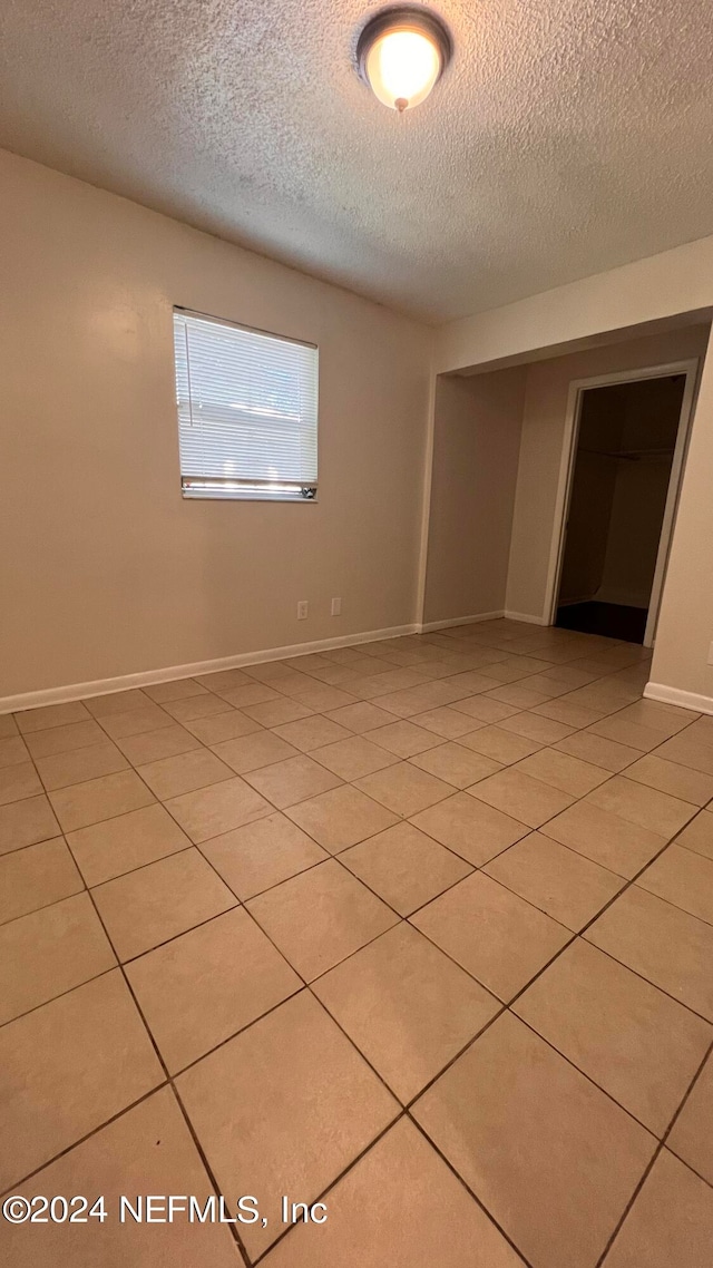 tiled empty room with a textured ceiling