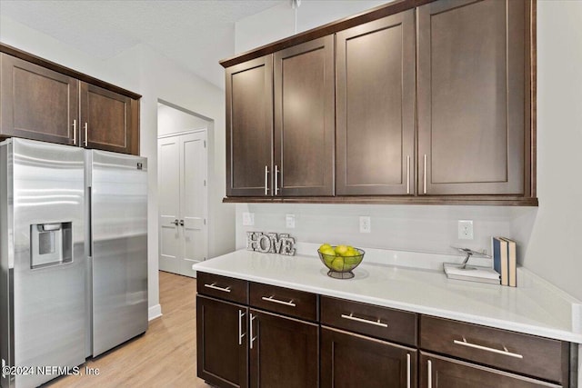 kitchen with dark brown cabinetry, light wood-type flooring, and stainless steel refrigerator with ice dispenser