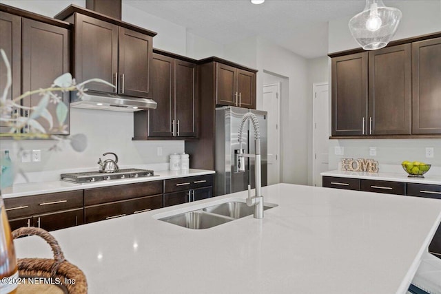 kitchen featuring hanging light fixtures, sink, dark brown cabinetry, appliances with stainless steel finishes, and a textured ceiling