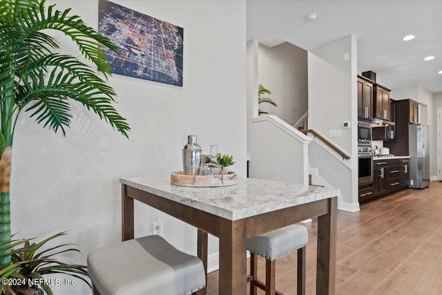 dining space featuring a textured ceiling and light hardwood / wood-style flooring