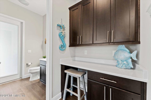 interior space with light hardwood / wood-style floors, dark brown cabinetry, and a breakfast bar area