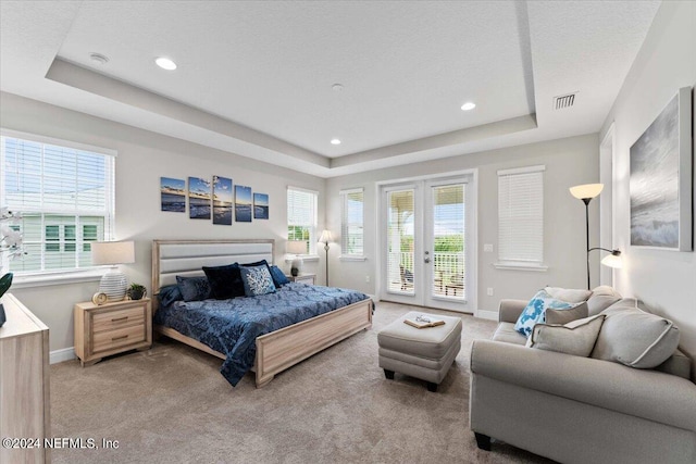 carpeted bedroom featuring french doors, a tray ceiling, access to outside, and multiple windows