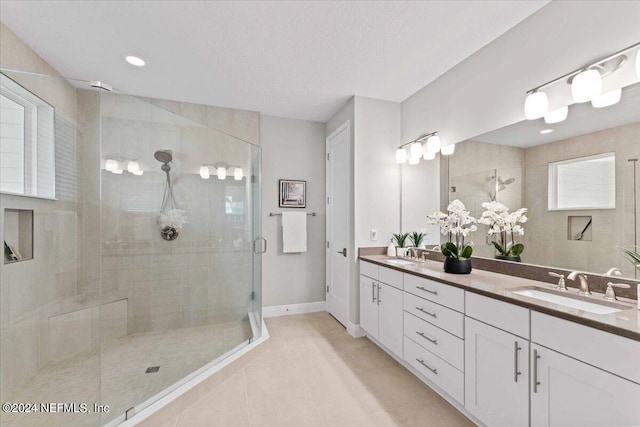 bathroom with vanity, a shower with shower door, a textured ceiling, and tile patterned floors