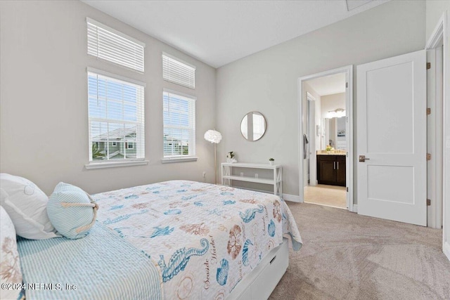 bedroom featuring ensuite bath and light carpet