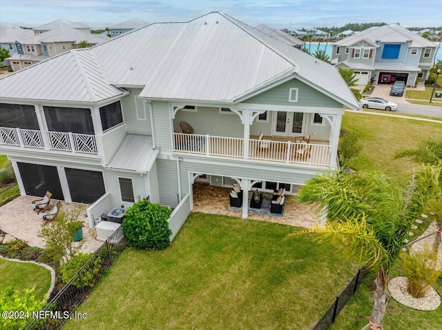 back of house with a sunroom, a lawn, a patio area, and a balcony