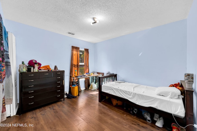 bedroom with a textured ceiling and dark wood-type flooring