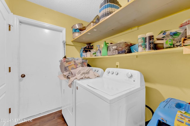 clothes washing area with washer and dryer, a textured ceiling, and dark wood-type flooring