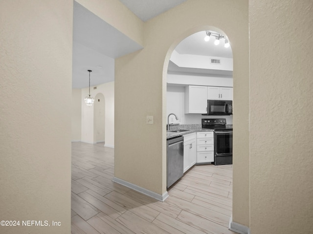 kitchen with appliances with stainless steel finishes, white cabinetry, sink, and decorative light fixtures