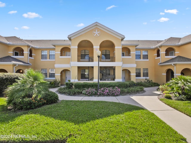 view of property with a balcony and a front yard