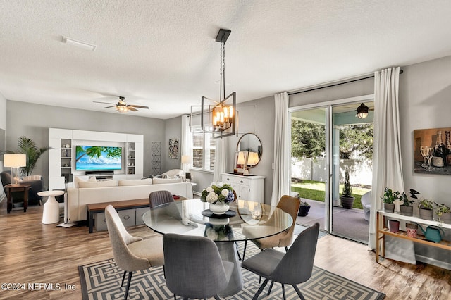 dining room featuring ceiling fan with notable chandelier, a textured ceiling, and hardwood / wood-style flooring