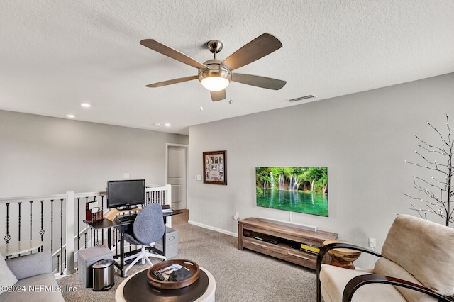 carpeted home office featuring a textured ceiling and ceiling fan