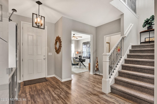 entryway featuring ceiling fan with notable chandelier and dark wood-type flooring