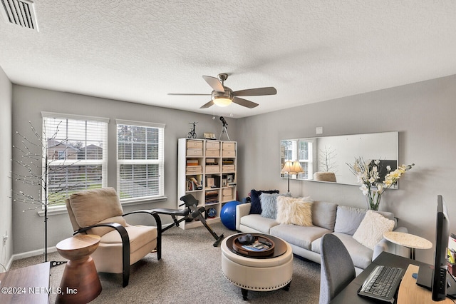 carpeted living room with ceiling fan and a textured ceiling