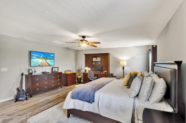 bedroom with ceiling fan, a textured ceiling, and light hardwood / wood-style flooring