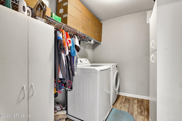 laundry area with light hardwood / wood-style floors, washing machine and dryer, and a textured ceiling