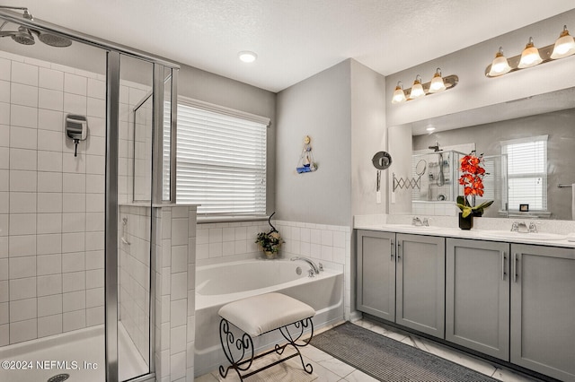 bathroom featuring tile patterned flooring, vanity, a textured ceiling, and plus walk in shower