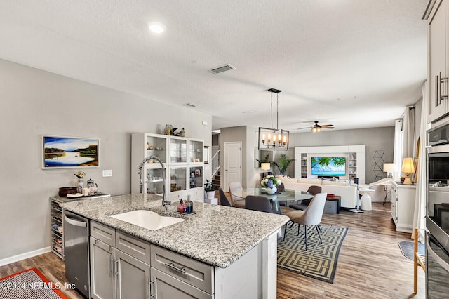 kitchen featuring light stone countertops, sink, dark hardwood / wood-style floors, and a center island with sink