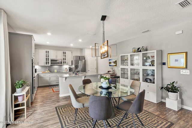 dining area with a chandelier, a textured ceiling, and hardwood / wood-style flooring