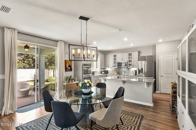 dining space with dark hardwood / wood-style flooring, a textured ceiling, and an inviting chandelier